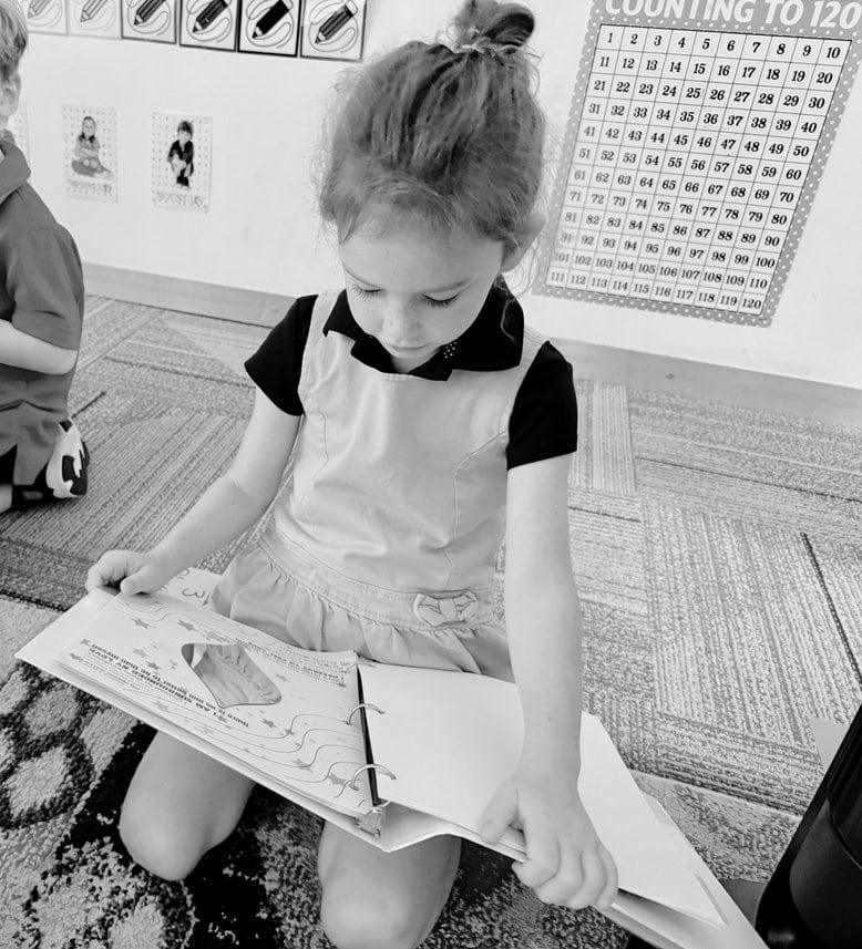A student sitting on the classroom floor with her SEL binder open on her lap.